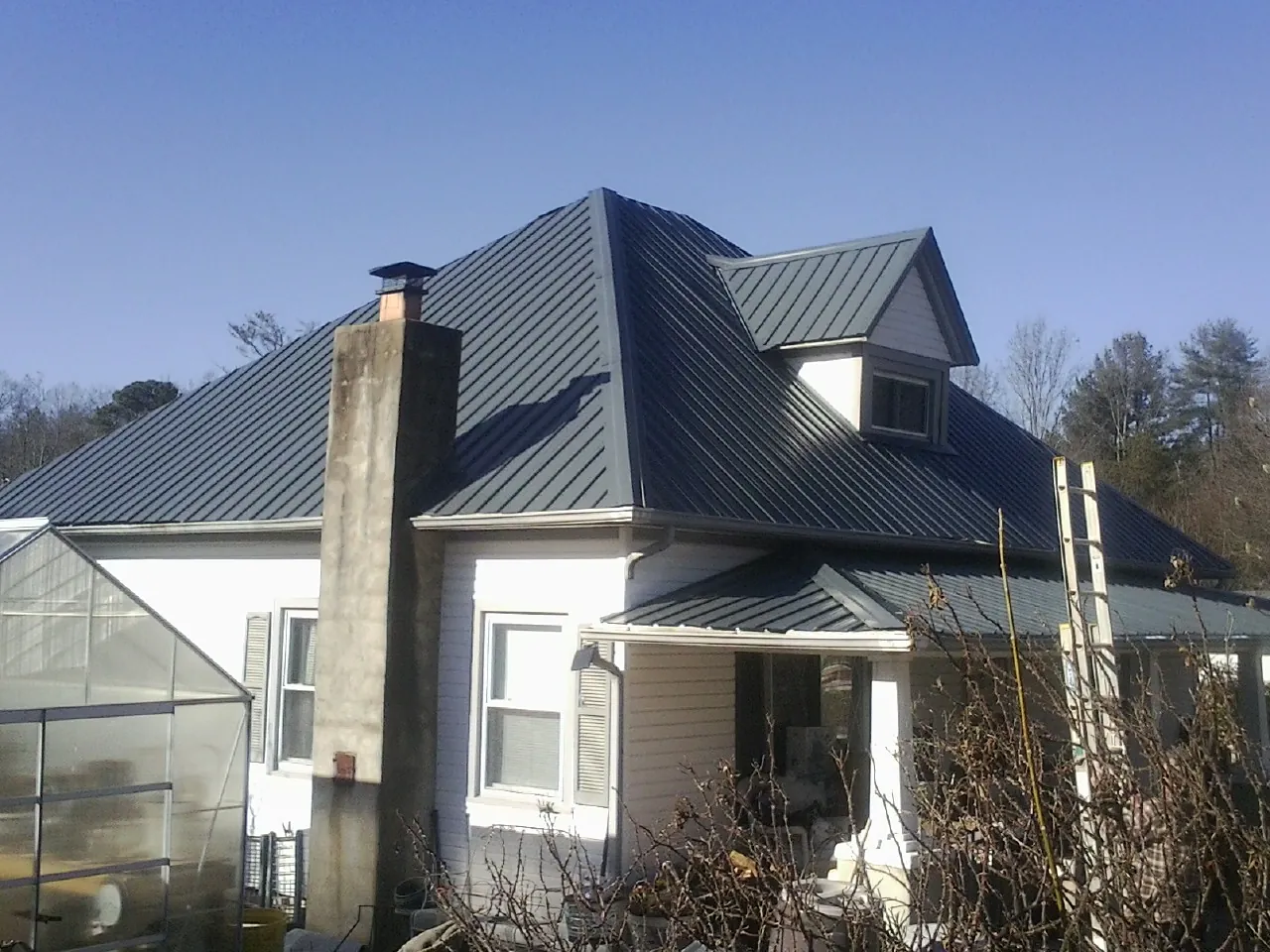 Dark blue standing seam metal roof on a white farmhouse with dormer — Slate & Tile Roof Repair by Roofing Brothers in Branch