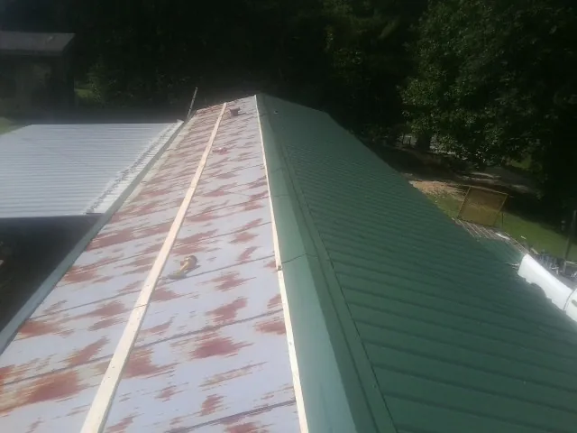 Old rusted panels beside newly installed green metal roofing — Wind Damage Roof Repair by Roofing Brothers in Branch