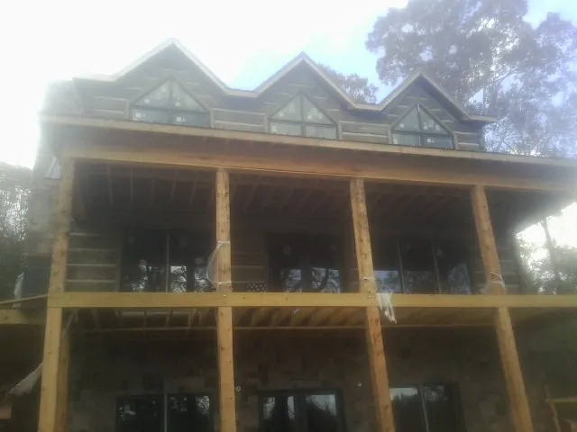 Dormers and porch framing on a large log home under construction — Roof Coating work by our crew in Branch