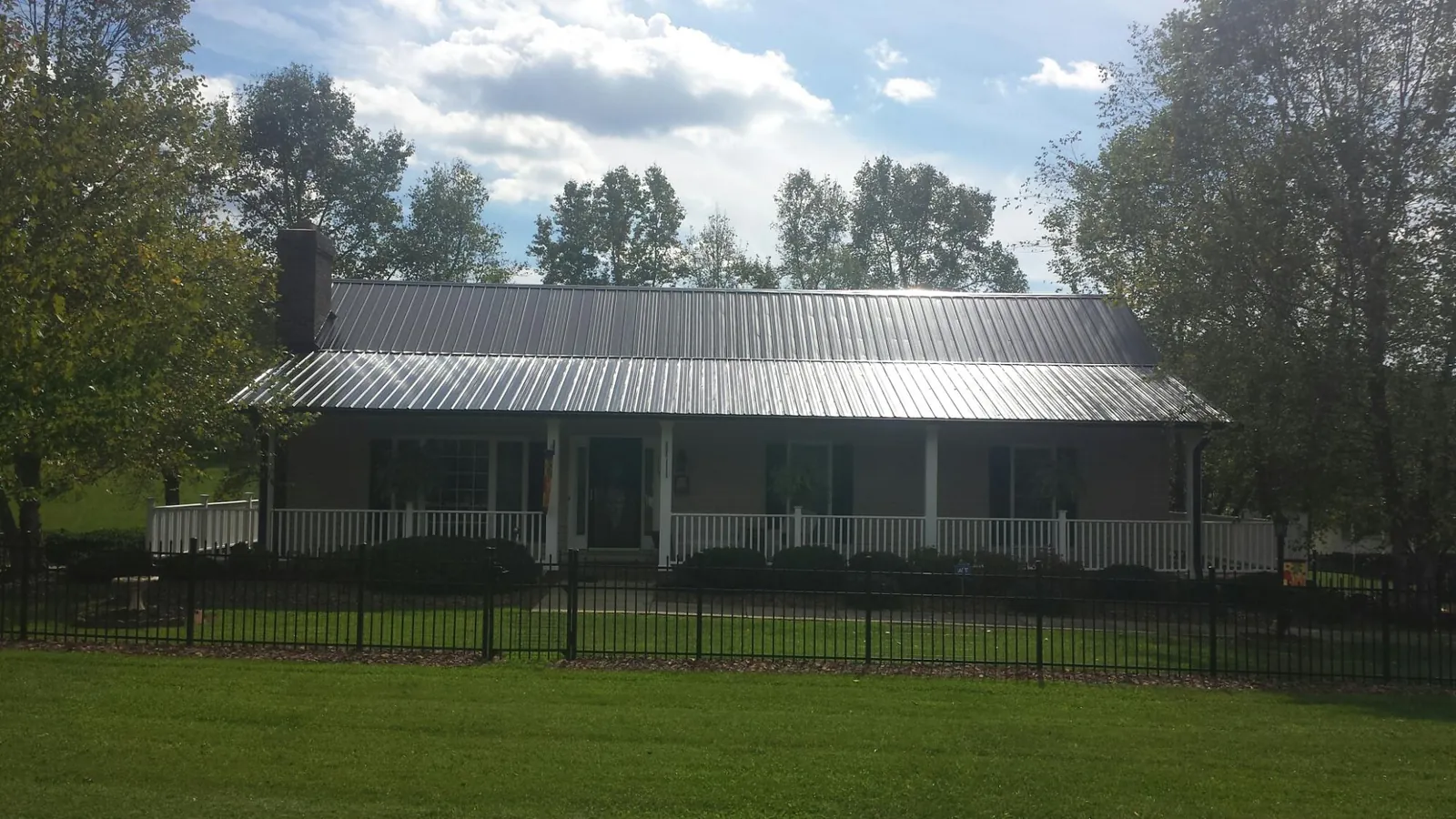 Gray metal roof on a brick ranch with a full width front porch — Gutter Guard Installation work by our crew in Branch